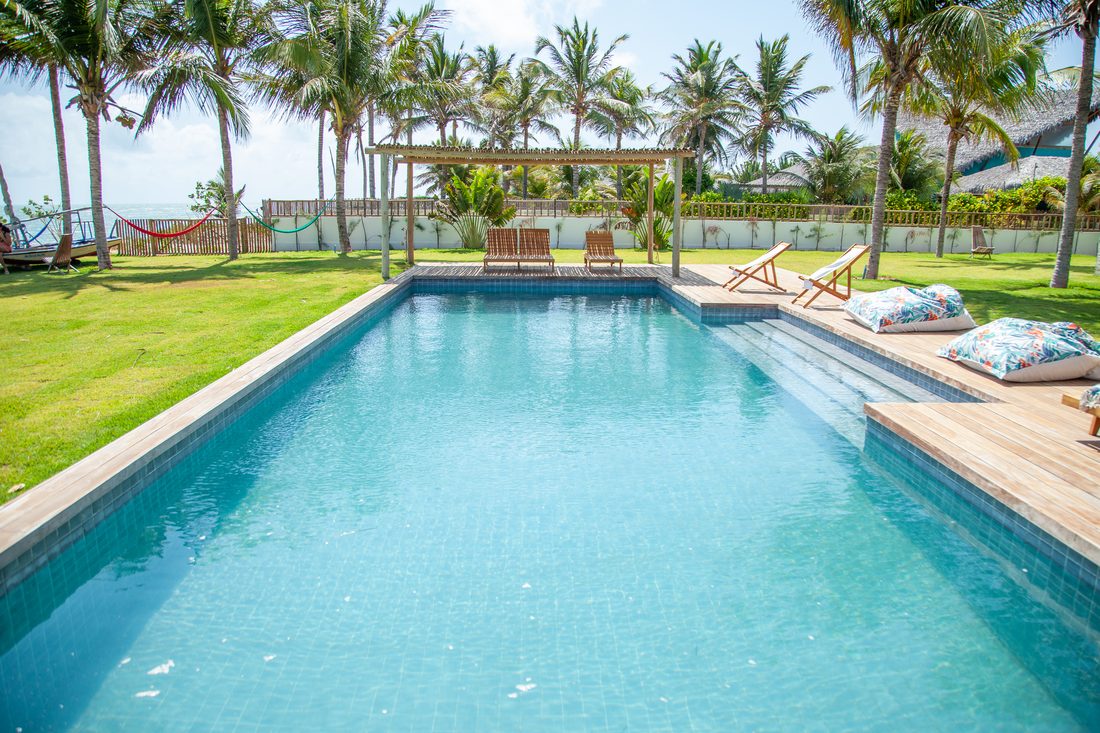 Ampla piscina privativa cercada de coqueiros